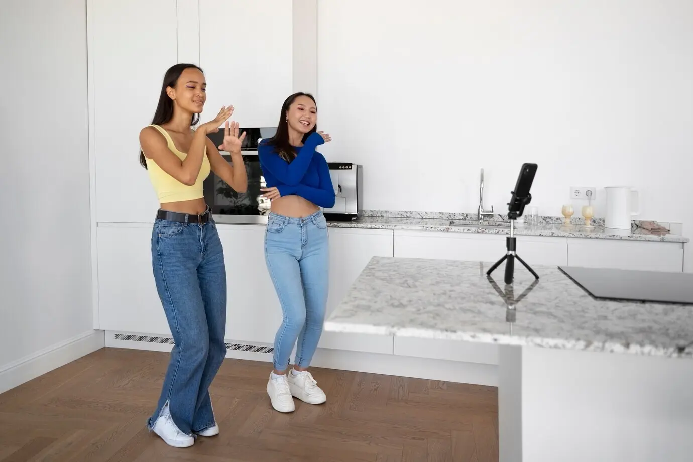 Lächelnde Mädchen tanzen zusammen, in einer Ganzkörperaufnahme.